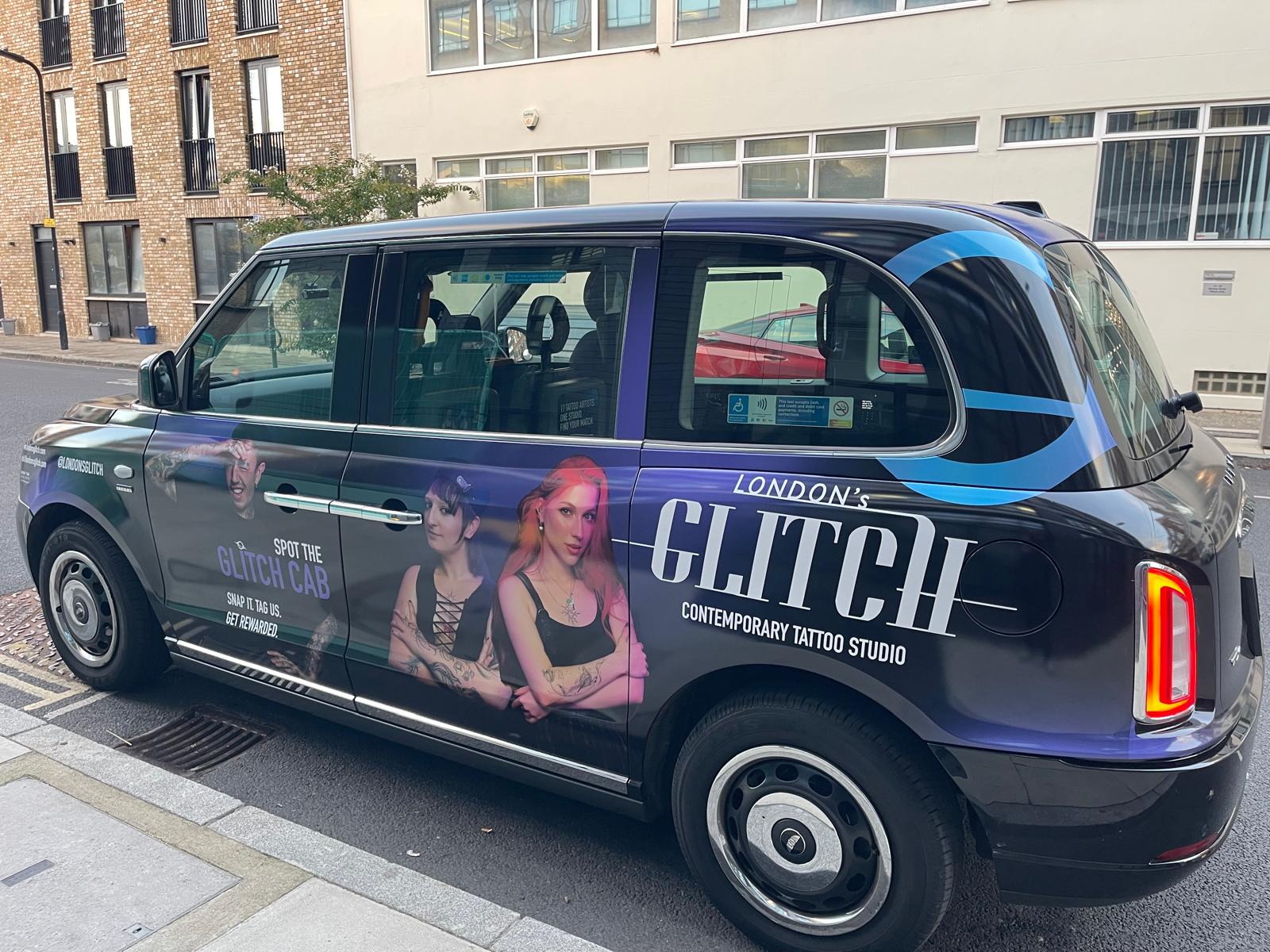 Rear three-quarter view of the branded London's Glitch black cab showing the studio logo and artists