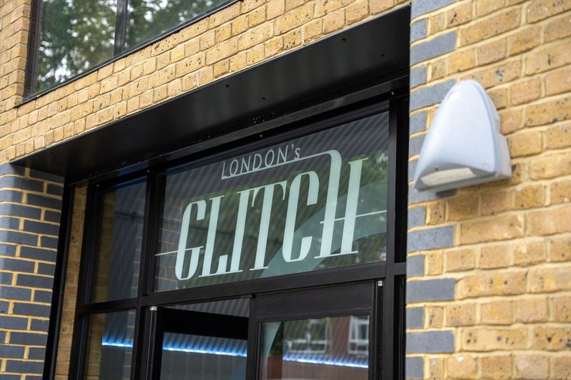 The London's Glitch window sign lit on the brick frontage