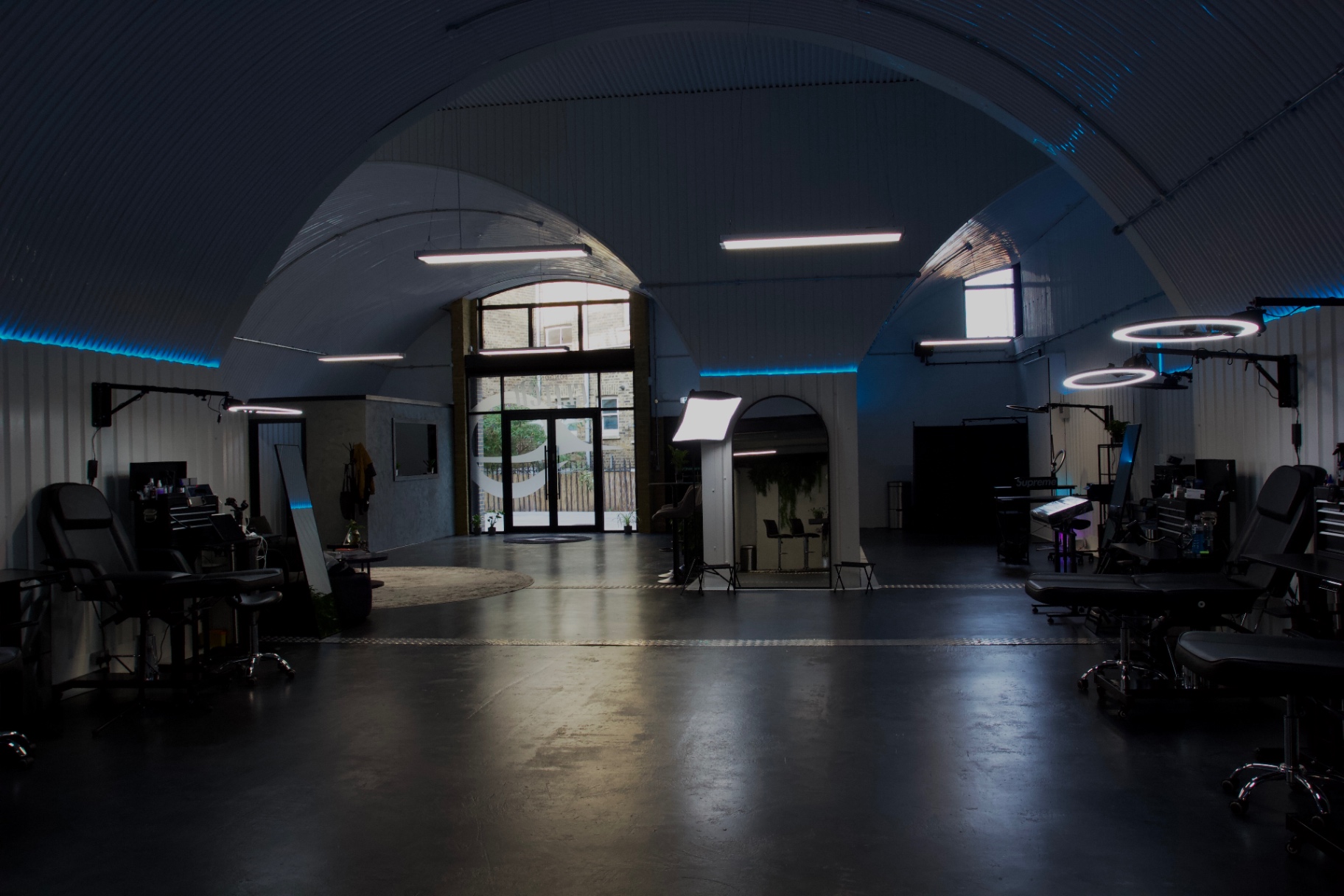 The finished open-plan tattoo floor at London's Glitch, black stations under the lit curve of the arch