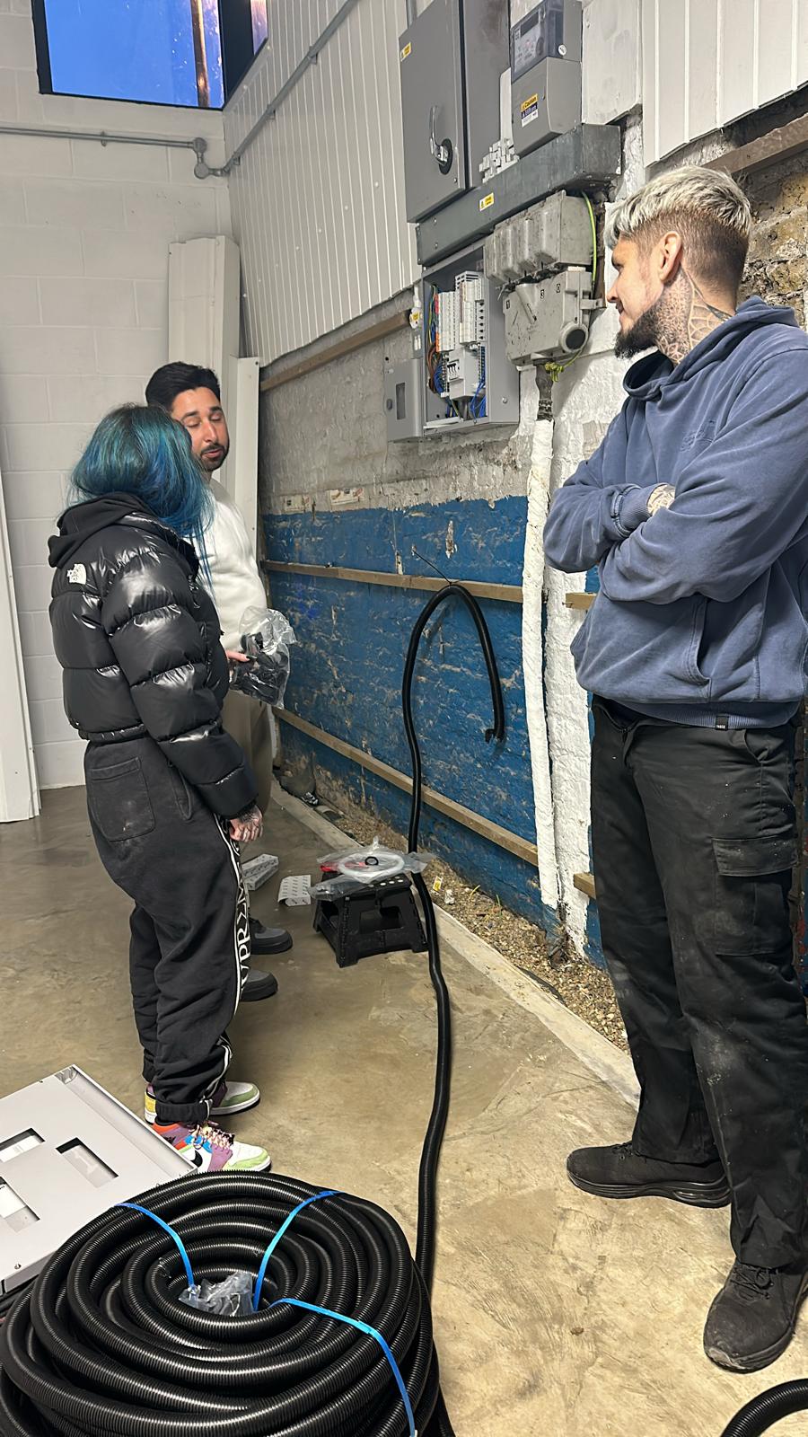 Clara and Roy working on the electrics at the wall with cable coiled on the floor