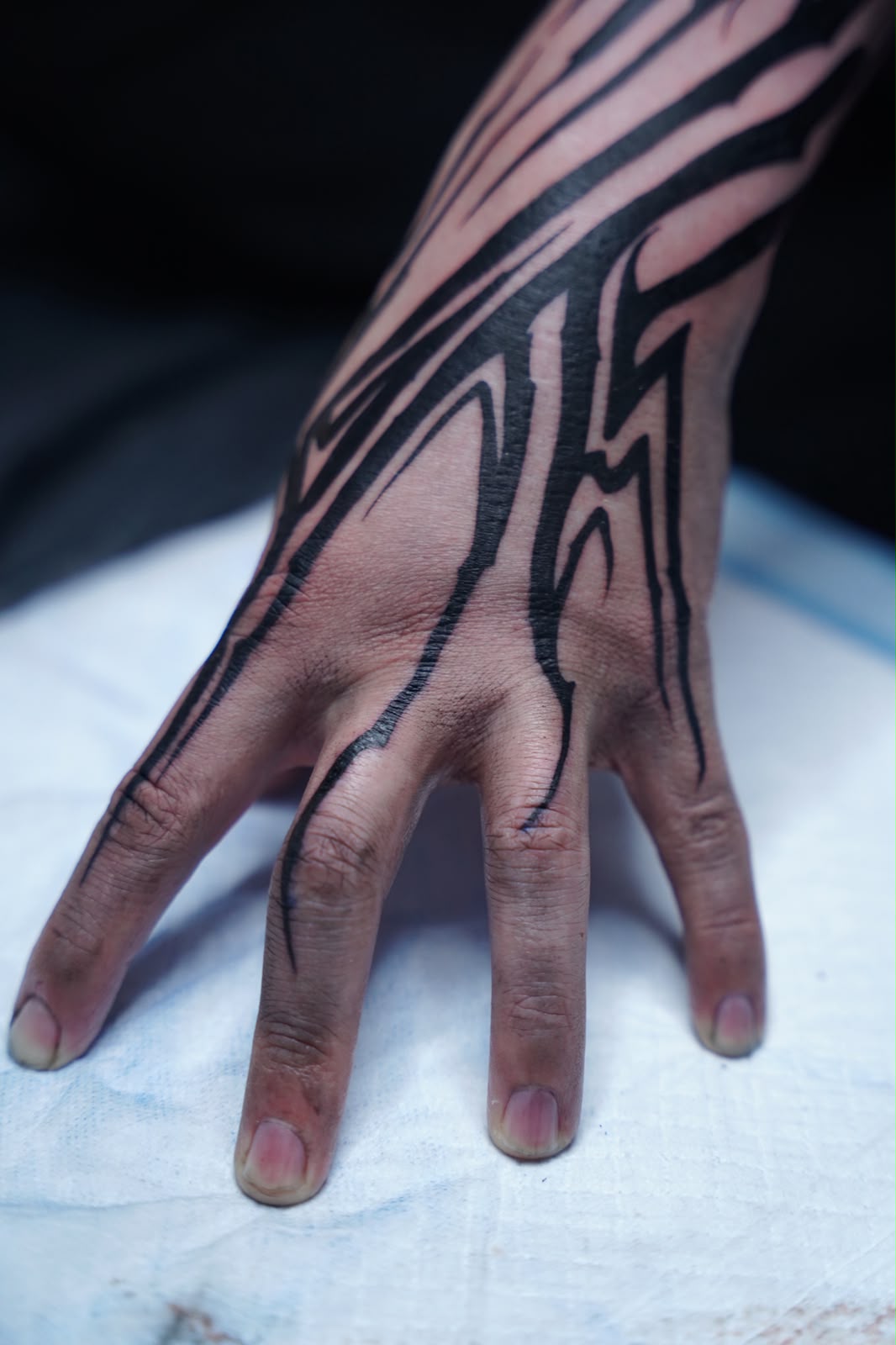 Neo-tribal blackwork tattoo across the back of the hand