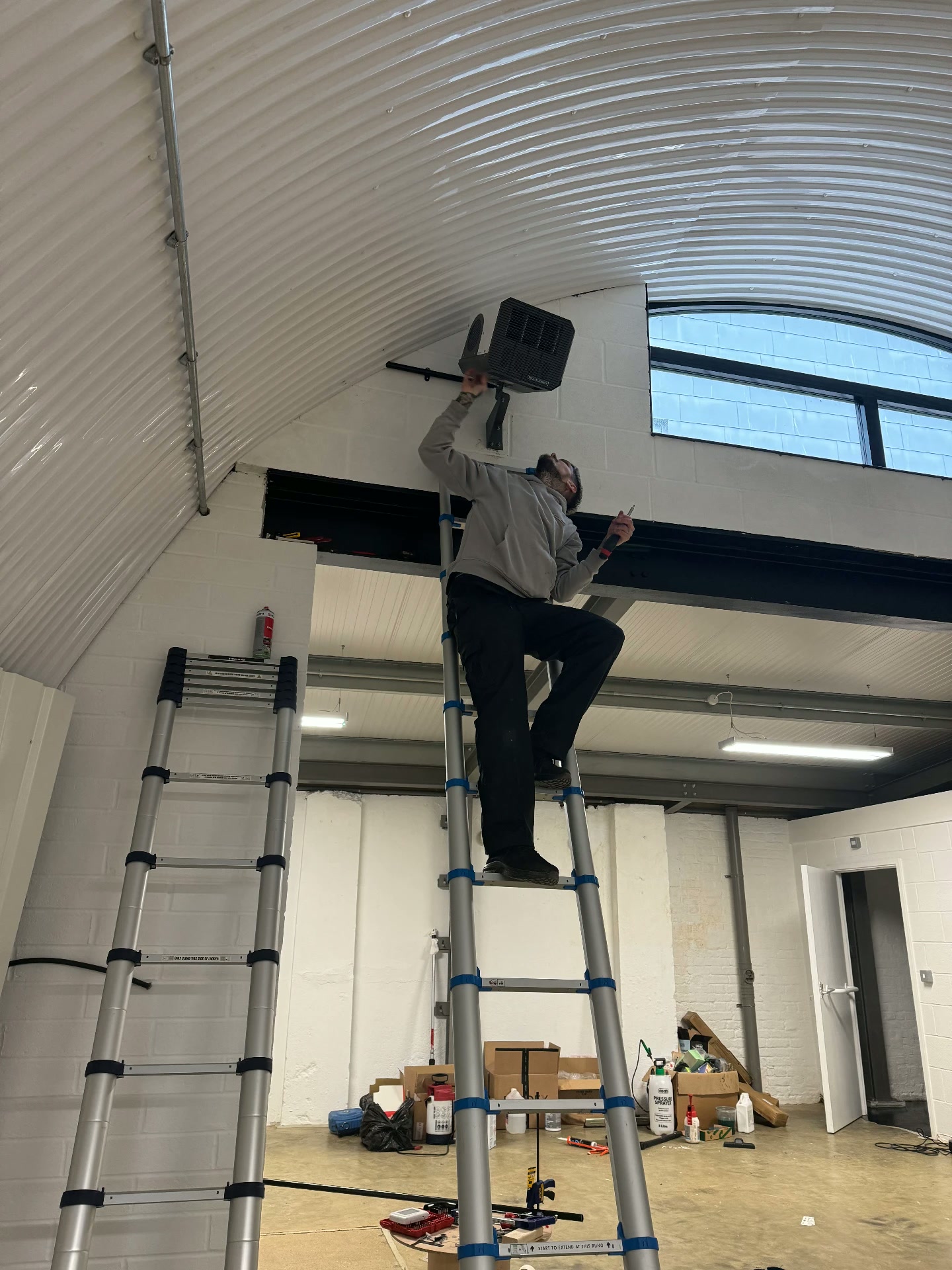 Standing on a ladder to mount a speaker high on the curved wall of the arch during the build