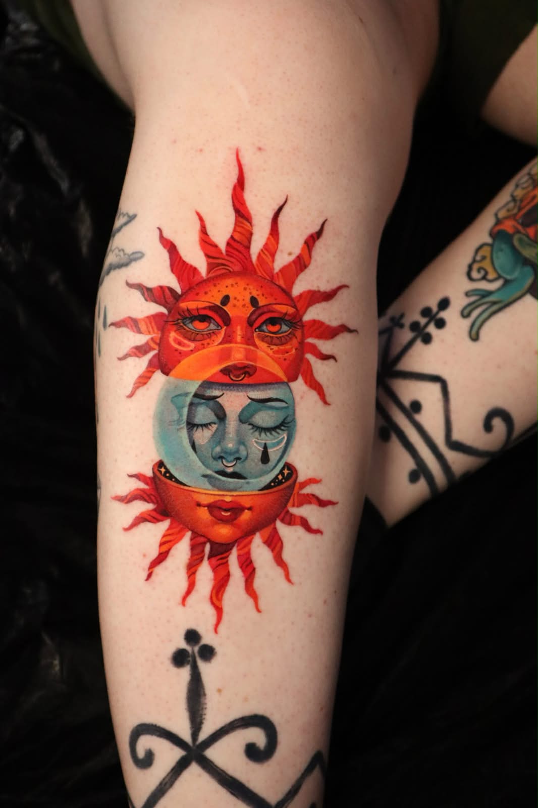 Colour tattoo of a sun and moon with faces on the forearm, tattooed at London's Glitch