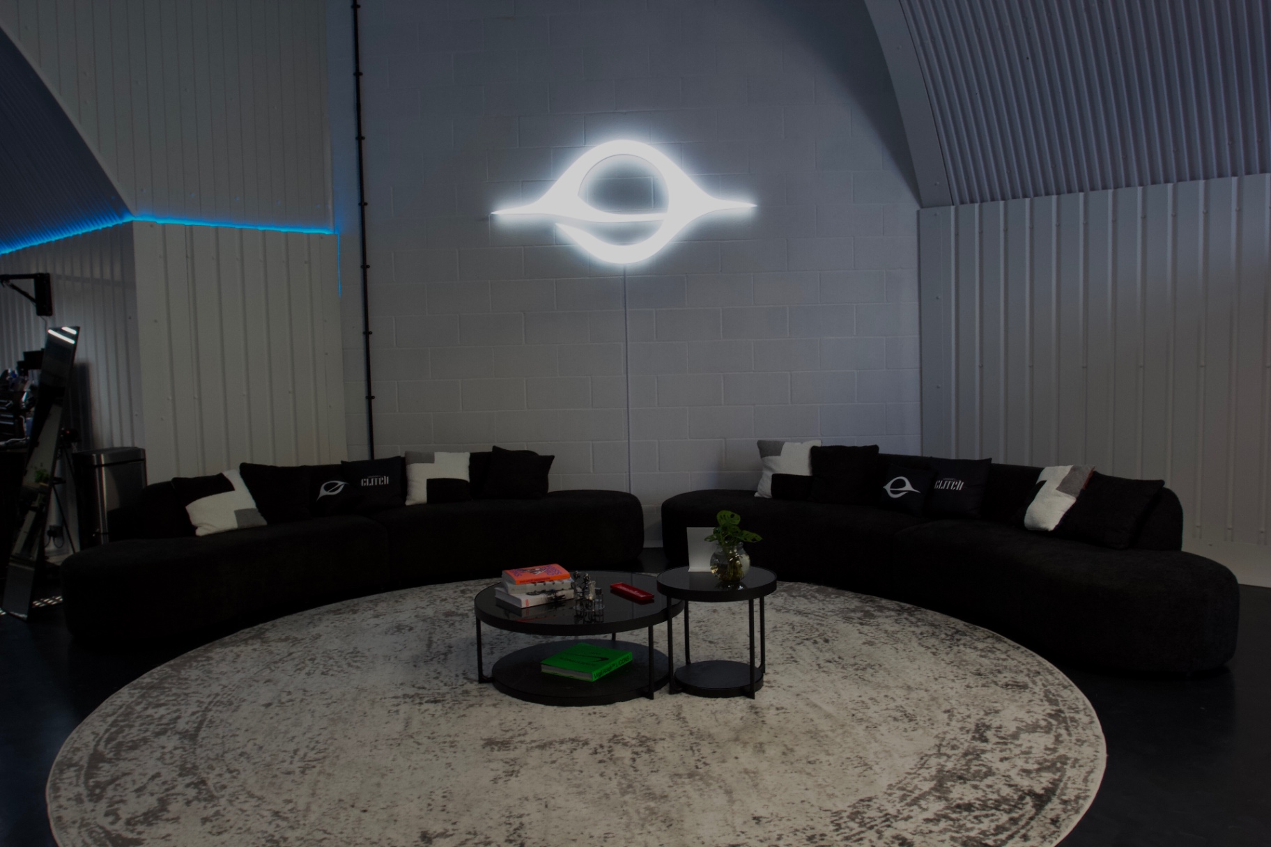 The client lounge with black sofas, rug and the glowing London's Glitch mark on the wall