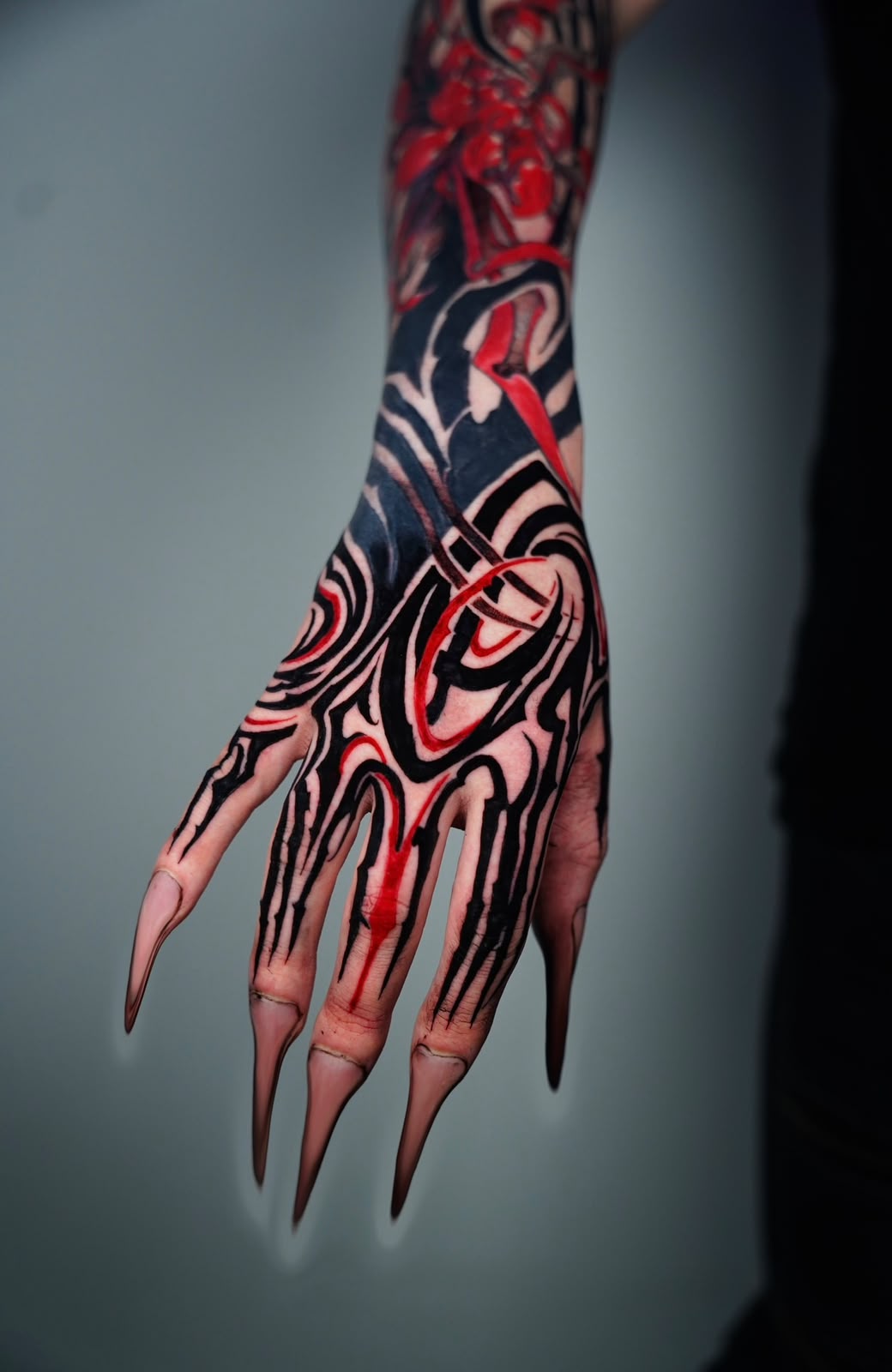 Neo-tribal blackwork hand and forearm tattoo with sharp flowing lines