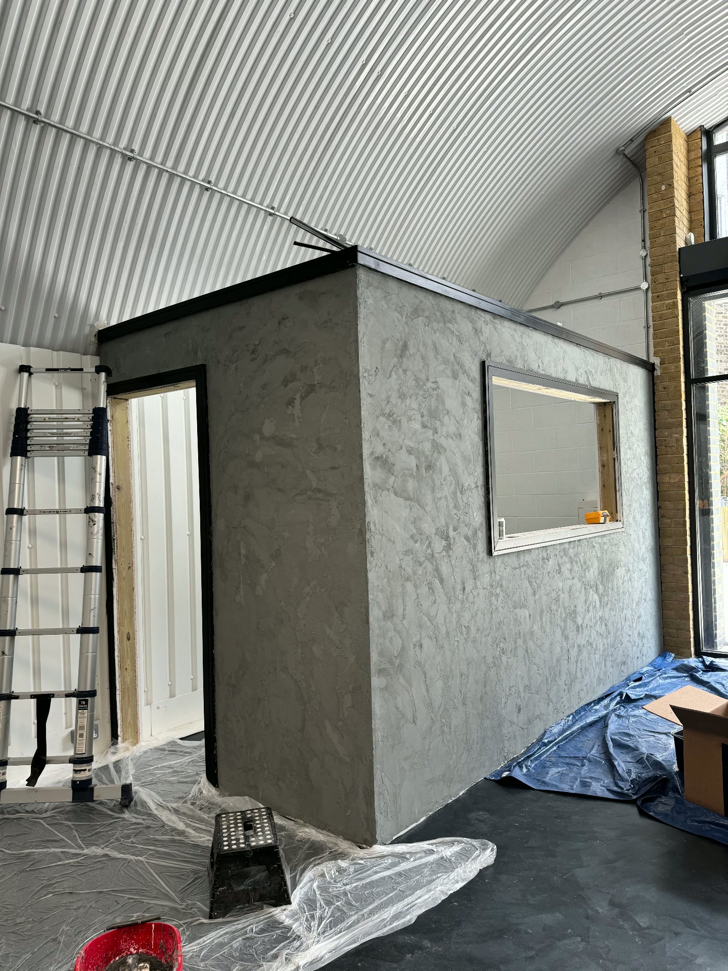 The shell of the private tattoo room part-built, dust sheets down over the floor