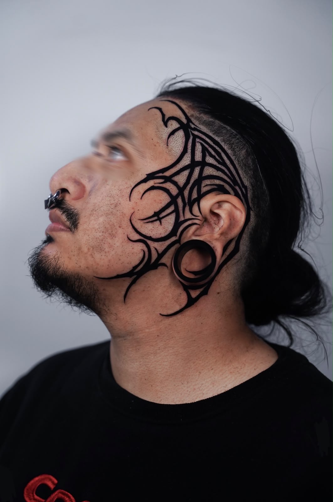 Neo-tribal blackwork tattoo on the side of the face and temple