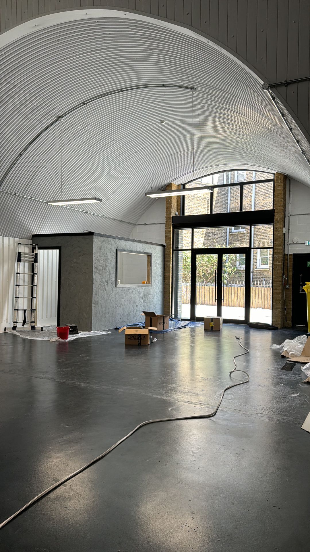 Raw arch interior with cabling coiled on the bare floor and daylight through the front doors
